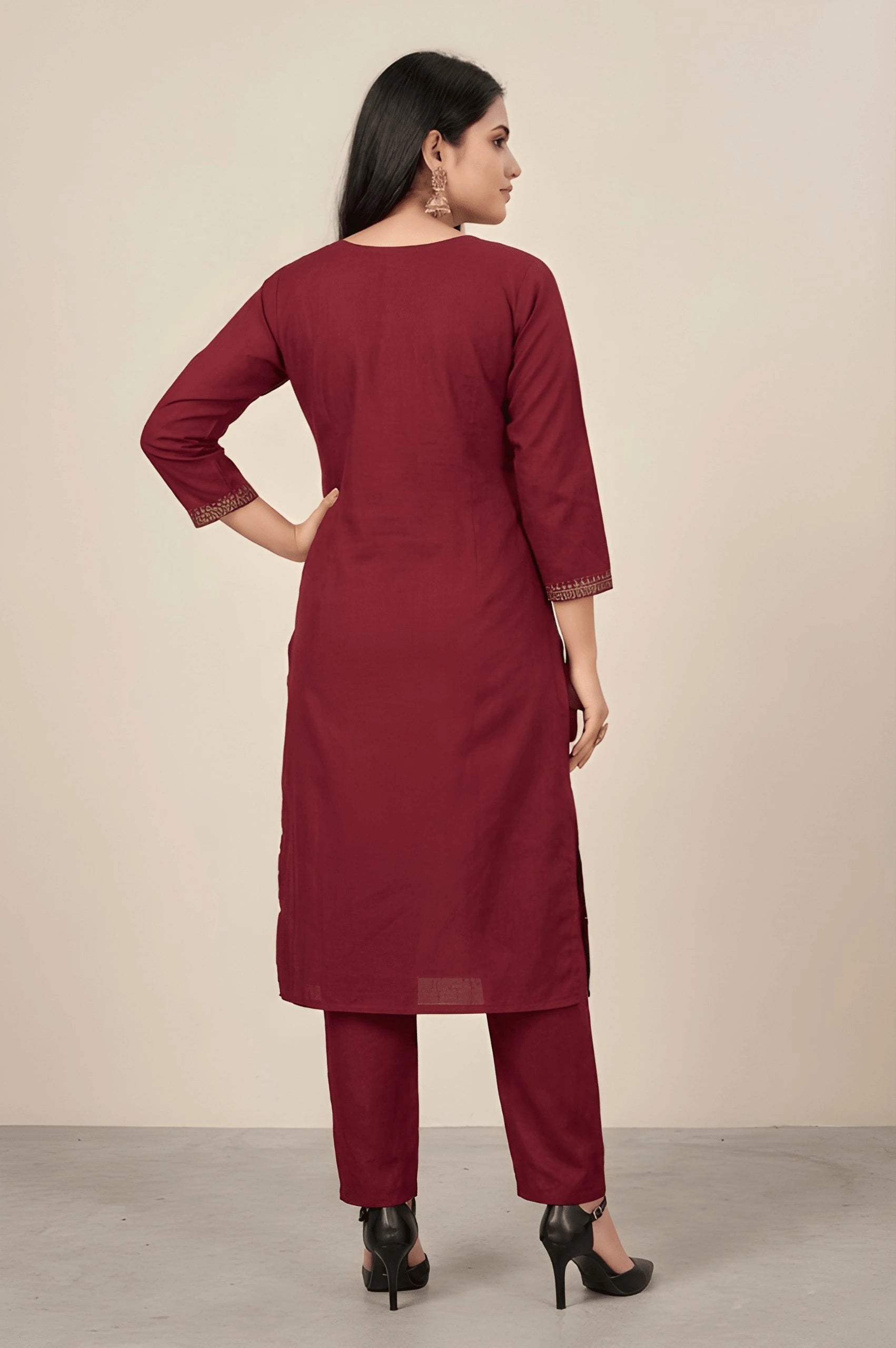Woman wearing a maroon kurta with matching pants against a beige background